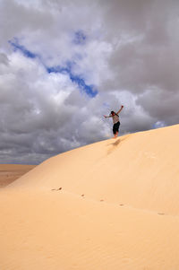 Man jumping at desert against sky