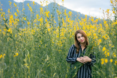 Portrait of beautiful young woman standing on field