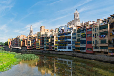 Buildings by river against sky in city