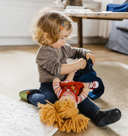 Girl playing with doll in living room at home