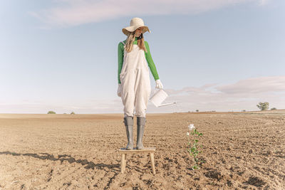 Rear view of woman standing on field against sky