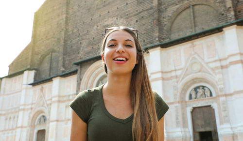 Portrait of smiling young woman standing against building