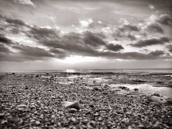 Scenic view of beach against cloudy sky