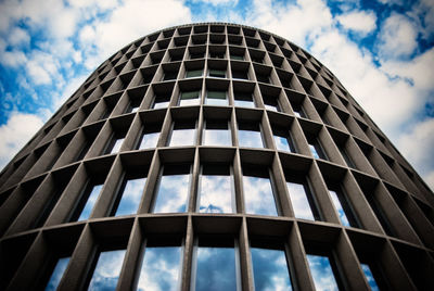 Low angle view of building with clouds reflection on windows