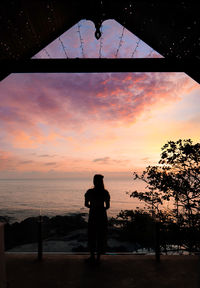 Rear view of silhouette man photographing sea against sky during sunset