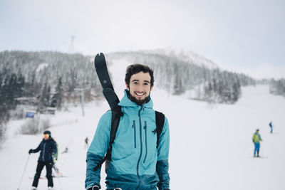 Portrait of smiling young man standing in snow