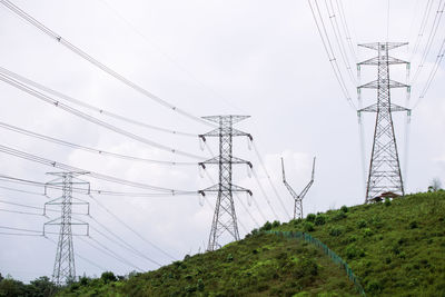 Low angle view of electricity pylons against sky