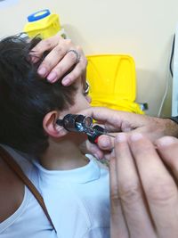 Cropped hands doctor checking ear of patient