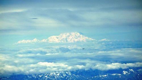 Snow covered landscape against cloudy sky