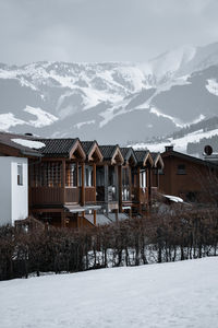 House by snowcapped mountains against sky