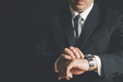 Midsection of man making face against black background