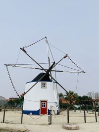Traditional windmill on beach against clear sky