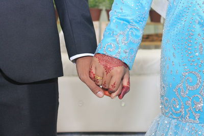 Midsection of bride and bridegroom holding hands during wedding ceremony