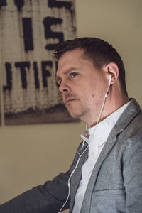 Portrait of young man looking away against wall