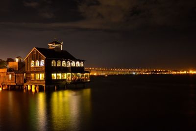 Illuminated stilt houses in river at night