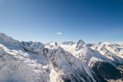 Scenic view of snowcapped mountains against clear blue sky