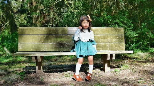 Full length portrait of girl standing on bench