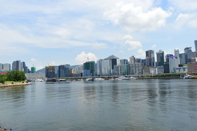 Sea by buildings in city against sky