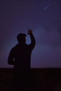 Rear view of silhouette man standing against sky at night