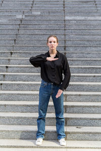 Portrait of beautiful young woman gesturing while standing against steps