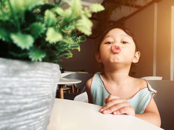 Portrait of cute girl sitting on table at home