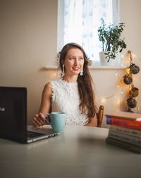 Young woman sitting on table at home