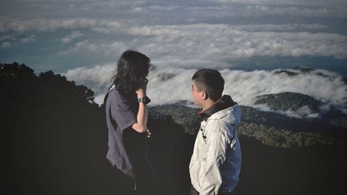 Friends standing on mountain against sea