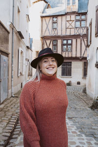 Portrait of smiling woman standing against building in city