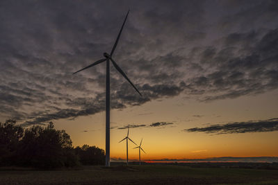 Windmill on field against sky during sunset