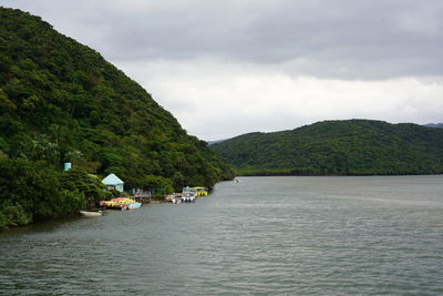 Scenic view of river by mountains against sky