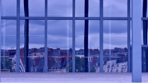 Buildings against sky seen through glass window