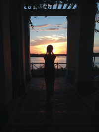 Silhouette of woman standing against sky at sunset