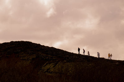 People walking on mountain against sky