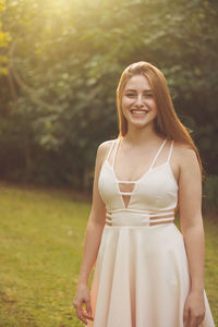 Portrait of young woman standing against trees