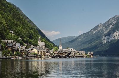 Scenic view of lake by buildings and mountains against sky