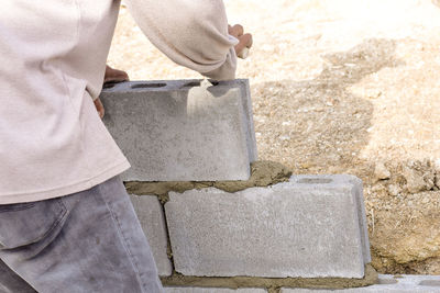 Midsection of man holding umbrella standing on concrete