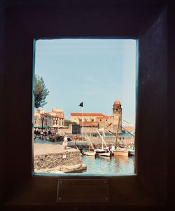 Buildings against sky seen through glass window