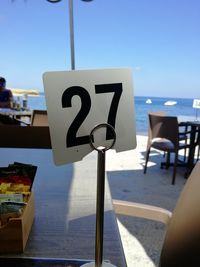 Close-up of information sign on beach against clear sky