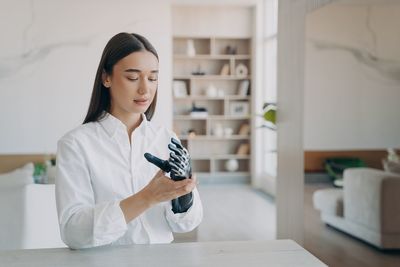 Portrait of young woman using mobile phone at home