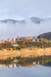 Typical residential buildings located on hill above calm river in scenic mountainous valley on sunny autumn day in riano