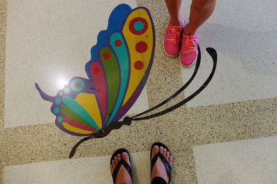 Low section of person standing on multi colored umbrella