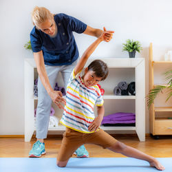 Lateral flexion exercise for children. boy exercising with physical therapist.