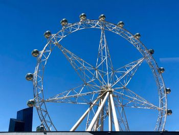 Low angle view of ferris wheel against blue sky