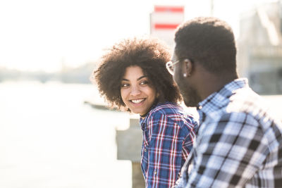 Young couple talking while sitting by lake