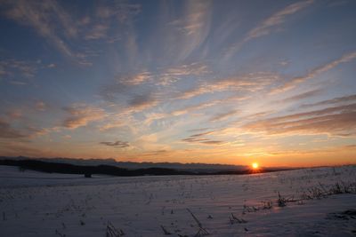 Scenic view of snow covered field against sky during sunset