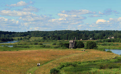 High angle view of man and woman walking on field against sky