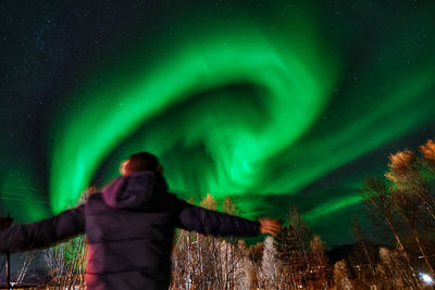 Rear view of mature man looking at aurora borealis in sky at night