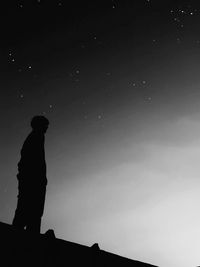 Low angle view silhouette of teenage boy standing against sky at night
