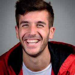 Close-up portrait of smiling young man against gray background