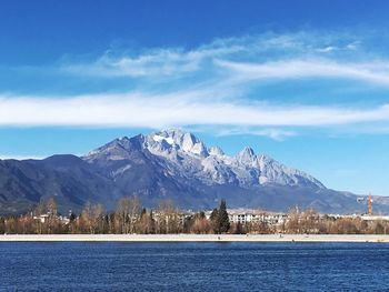 Scenic view of lake by snowcapped mountains against sky